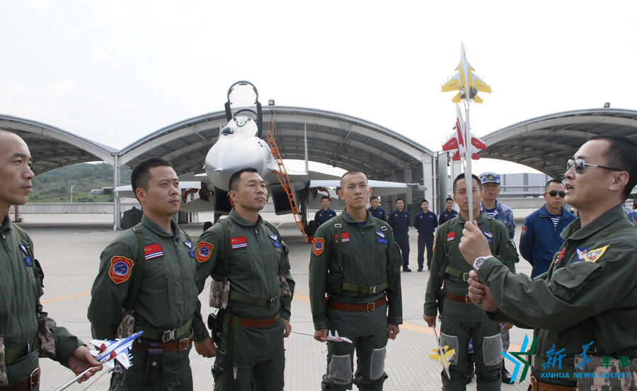 ↑艦載航空兵某部司令員戴明盟向飛行員演示空中飛行注意事項。