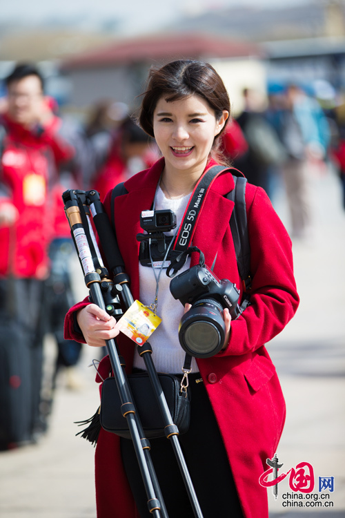 2016年兩會，人民大會大堂前，一位笑容燦爛的紅衣女記者正步入大會堂。中國網 鄭亮 攝